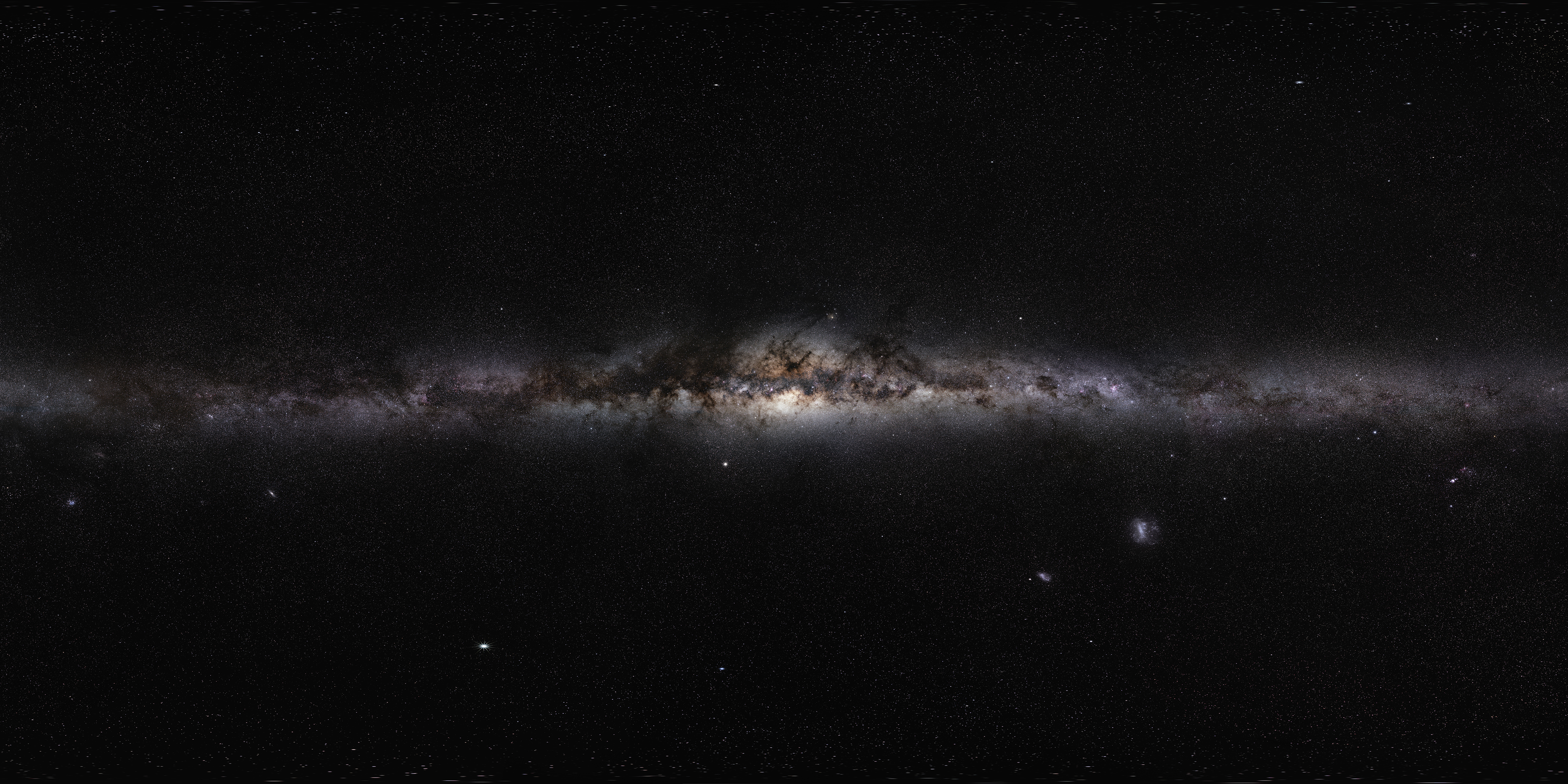 Wide panoramic view of the Milky Way band stretching across a dark night sky, with many stars and dark dust lanes.