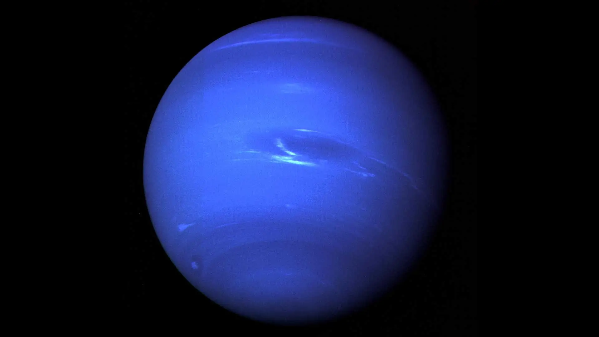 Image of Neptune showing a deep blue disk with bright clouds and a dark storm feature.