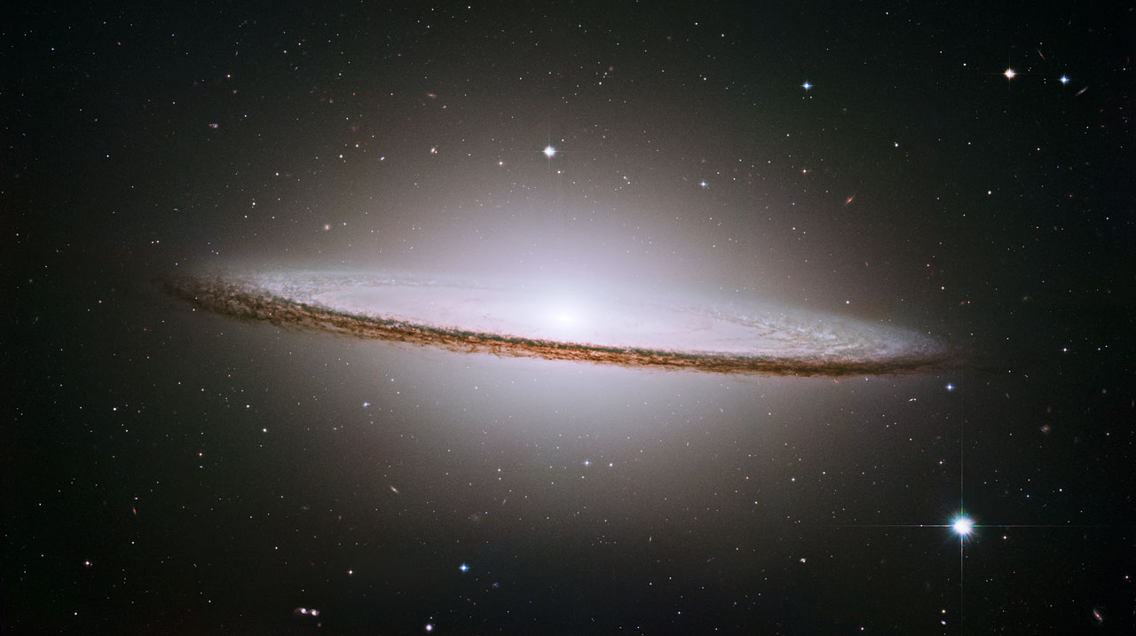 Hubble image of the Sombrero Galaxy seen nearly edge-on, with a large bright central bulge and a thin dark dust lane across the disk.