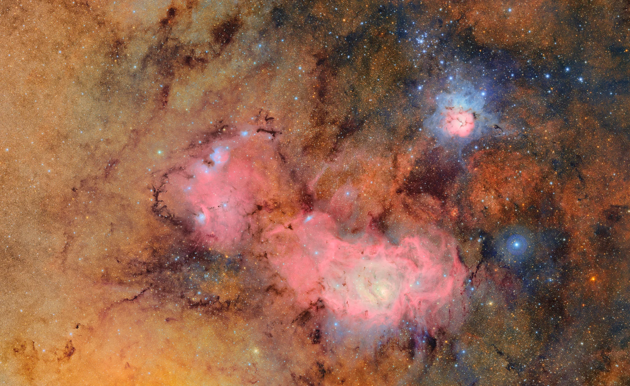 Rubin Observatory’s First Light on the Lagoon and Trifid Nebulae. This iconic first-release image from the Rubin Observatory captures the vivid interplay of nebulae, dust, and star clusters in Sagittarius. Notice how the rich reds and pinks trace hydrogen-alpha emission (656 nm), pinpointing regions of active star formation and ionized gas. Blue and turquoise tones correspond to reflected starlight and glowing oxygen ([OIII], 495–501 nm), while the dark lanes and golden clouds reveal dense, dusty regions where visible light is heavily absorbed, causing stars to appear reddened. The diversity of colors across the field demonstrates how visible wavelengths uncover the complex physics of ionization, scattering, and extinction in the galactic plane. (Image Credit: Rubin Observatory, First Public Release)